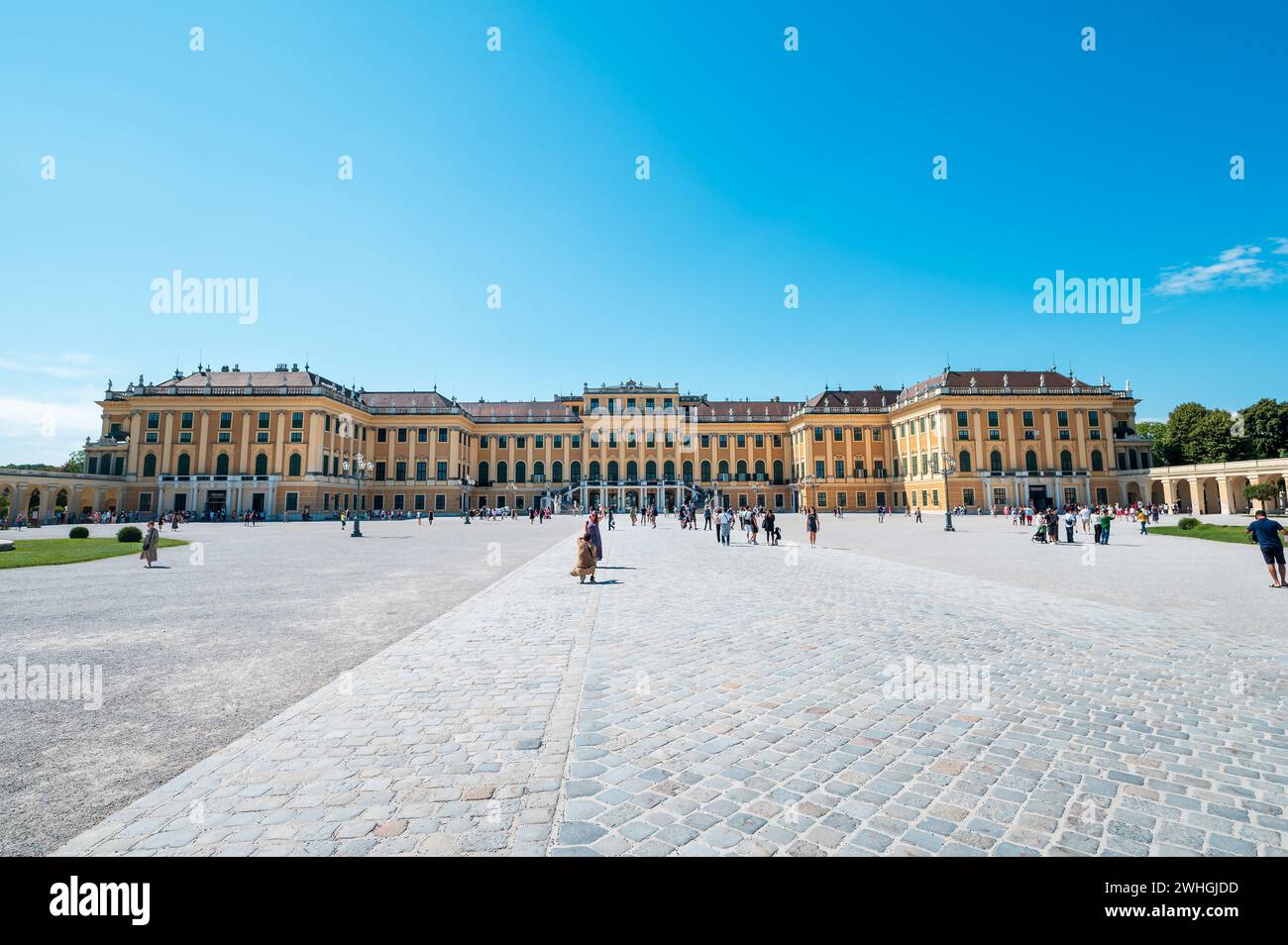 Vienna, Austria - 12 agosto 2022: Il palazzo Schönbrunn di Vienna si erge su una vivace piazza della città mentre la gente si riunisce sotto il cielo estivo, ammirando il gr Foto Stock
