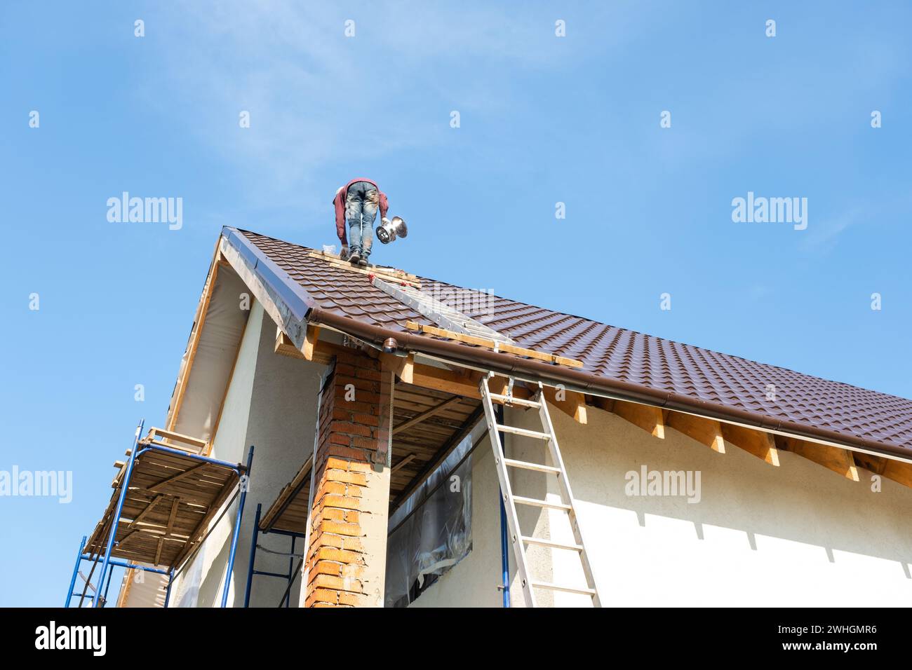 Il master per l'installazione dei tubi di ventilazione e l'installazione del camino del forno opera sul tetto del Foto Stock