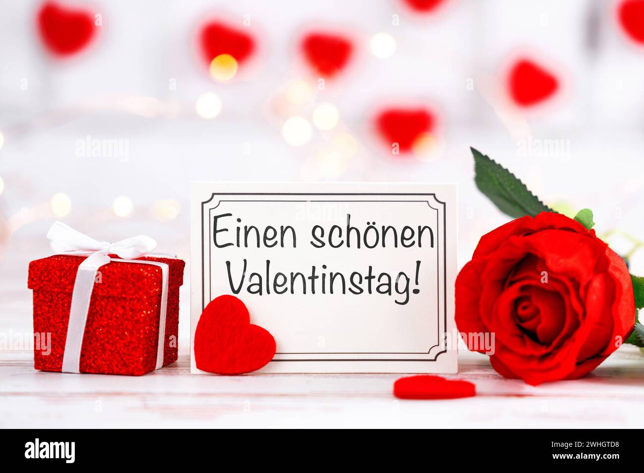 10 febbraio 2024: Saluto di San Valentino su un biglietto di auguri accanto a un regalo e una rosa rossa FOTOMONTAGE *** einen schönen Valentinstag Gruß auf einer Grußkarte neben einem Geschenk und einer roten Rose FOTOMONTAGE Foto Stock