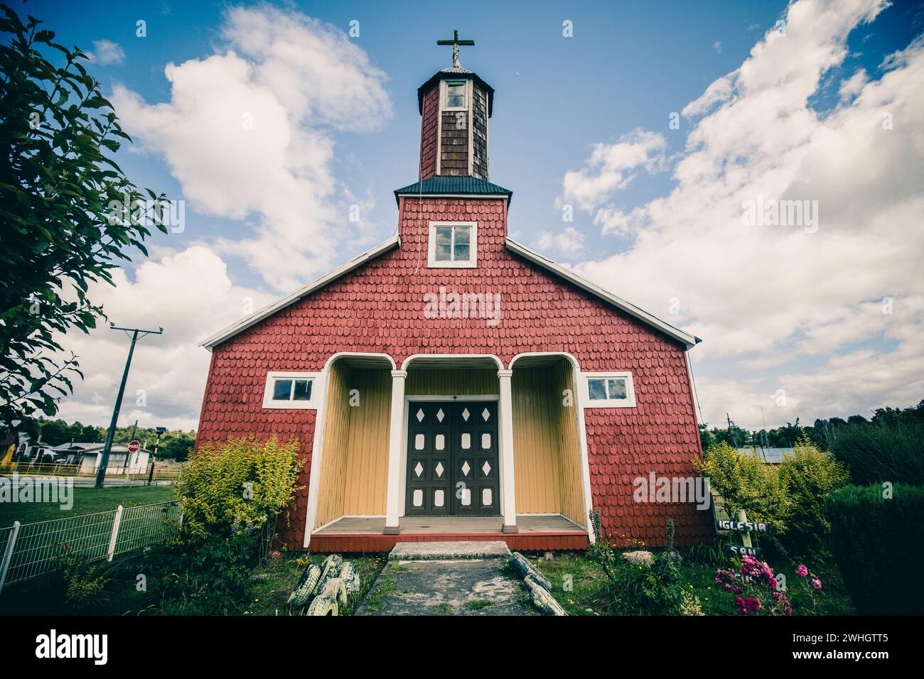 Chiesa in legno su Chiloe con una facciata rossa, colonne bianche nell'area d'ingresso e una croce di legno sulla torre. Foto Stock