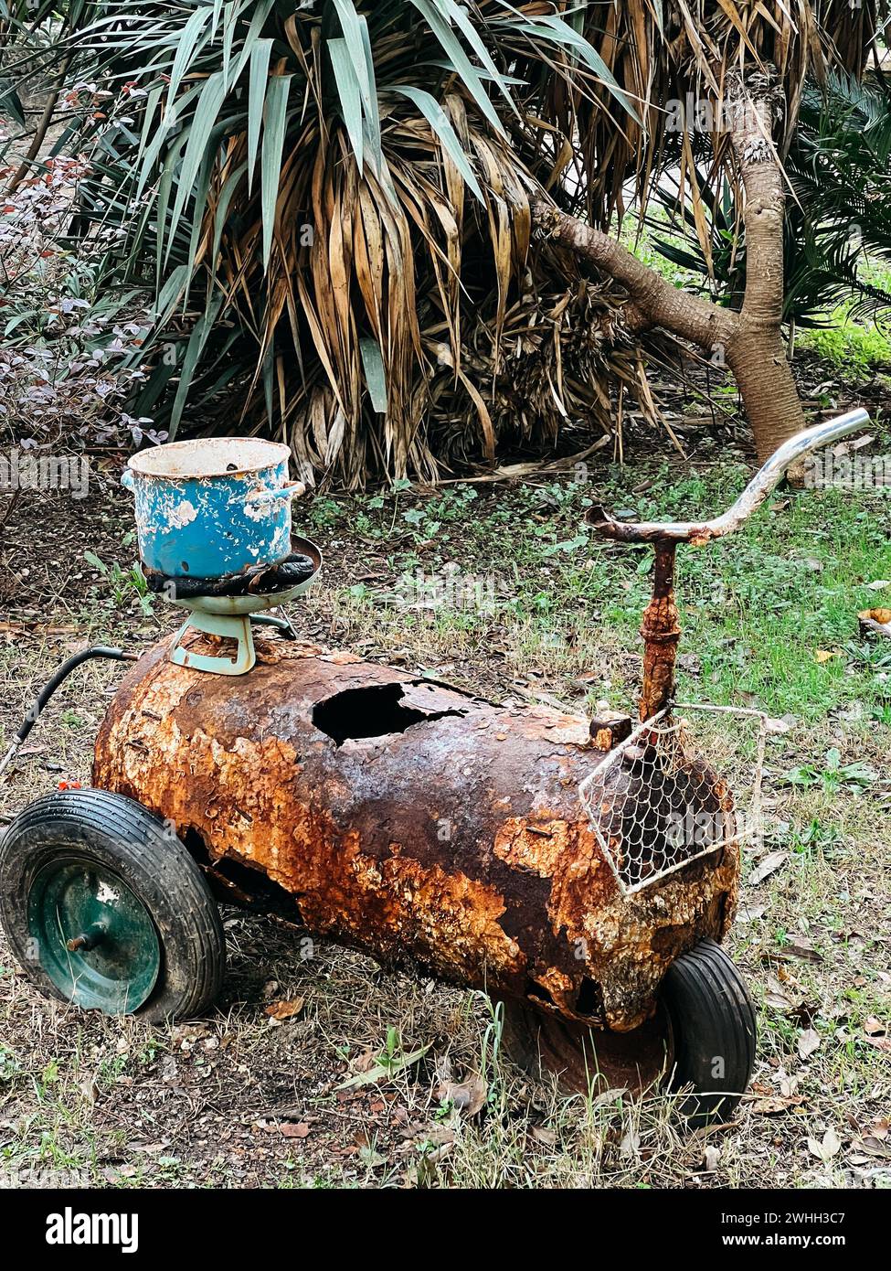 Vecchio serbatoio dell'acqua arrugginito sulle ruote con un supporto volante in giardino Foto Stock