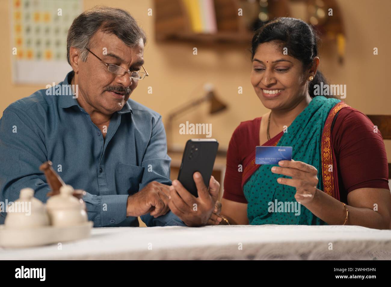 Coppia anziana che effettua acquisti online di e-commerce su telefono cellulare utilizzando carta di credito a casa - concetto di transazione sicura, finanziario o bancario Foto Stock
