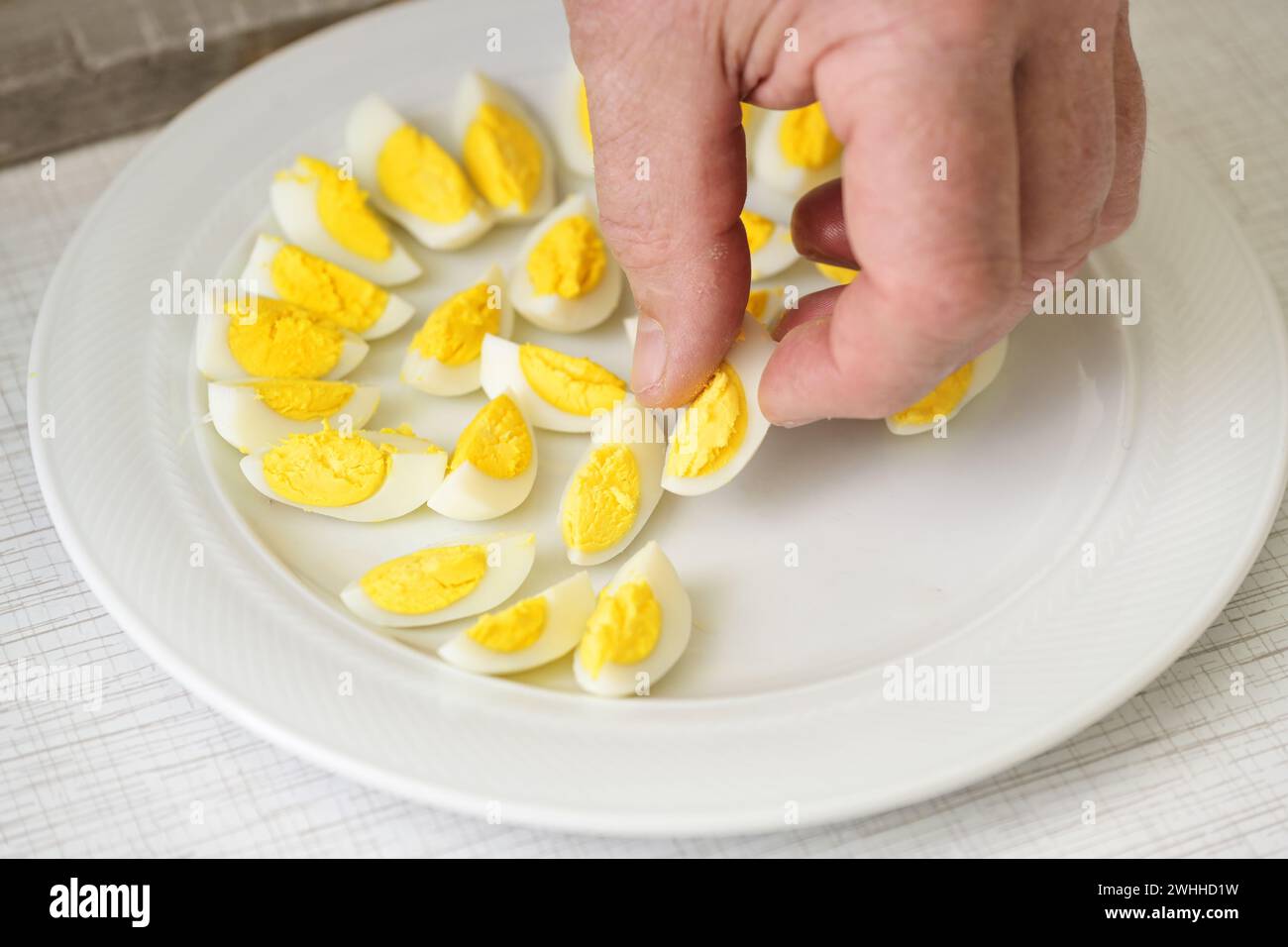 Posiziona a mano le uova di quaglia in quattro su un piatto per colazione, brunch o buffet per feste, focalizzazione selezionata Foto Stock