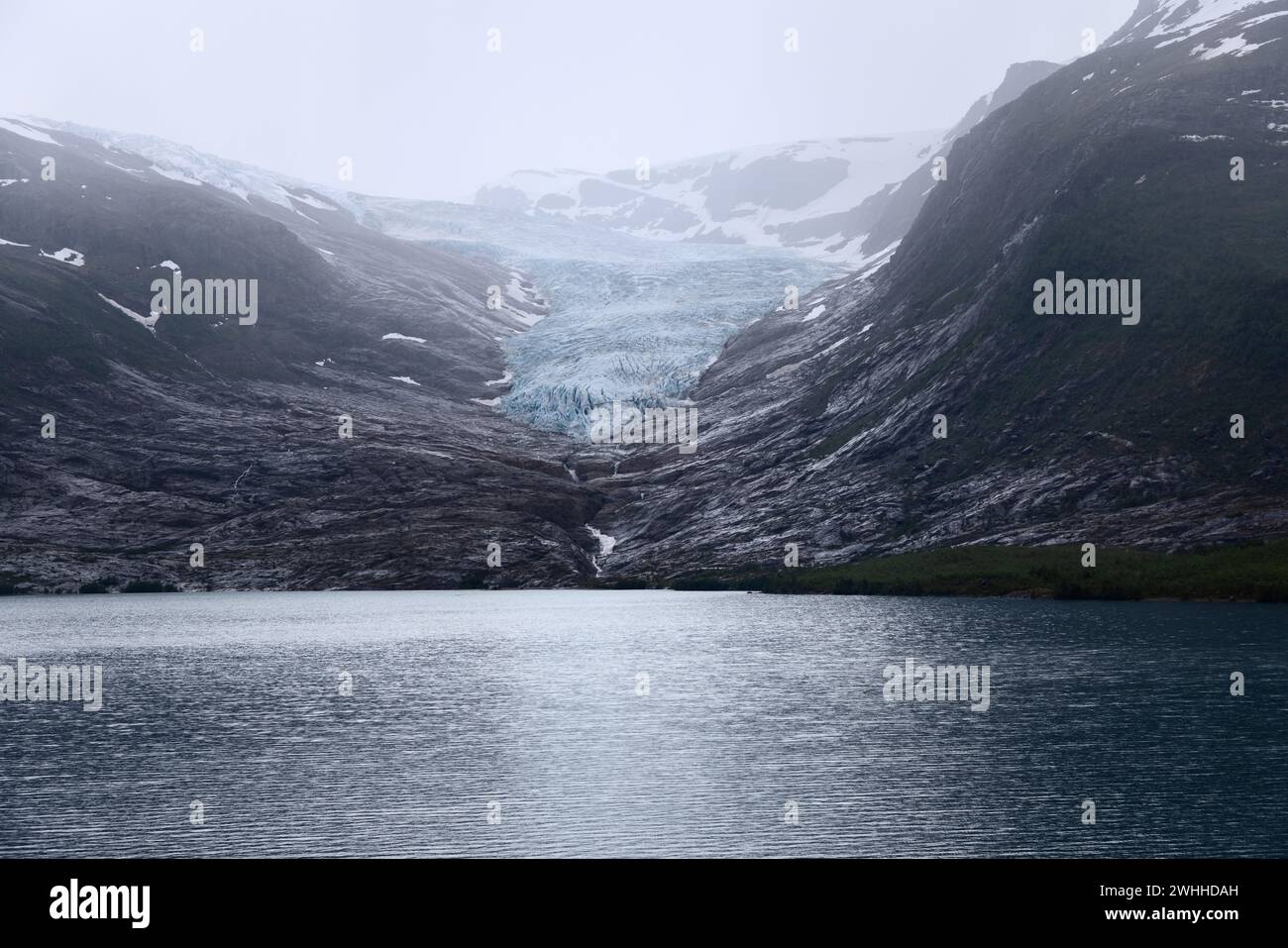 Il ghiacciaio Svartisen, una distesa ghiacciata scintillante, sfocia in un lago simile a uno specchio sullo sfondo aspro delle montagne norvegesi Foto Stock