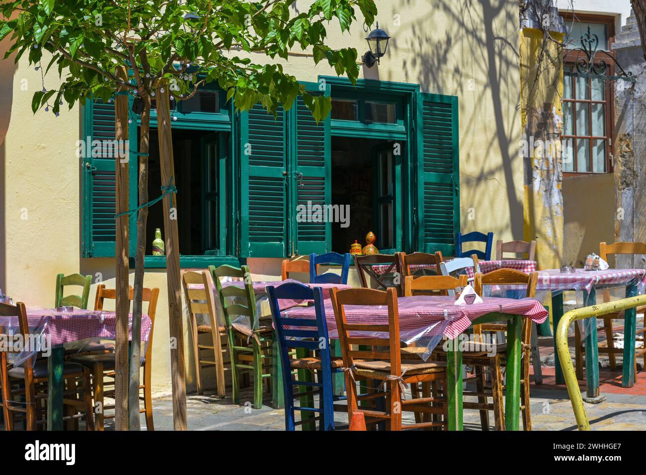 Rustica taverna mediterranea o informale ristorante di strada con diverse sedie di legno dipinte ai tavoli di fronte al windo Foto Stock