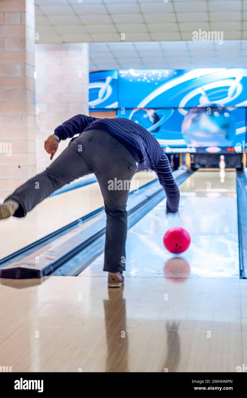 Ragazzo da dietro che gioca a bowling in pista da solo Foto Stock