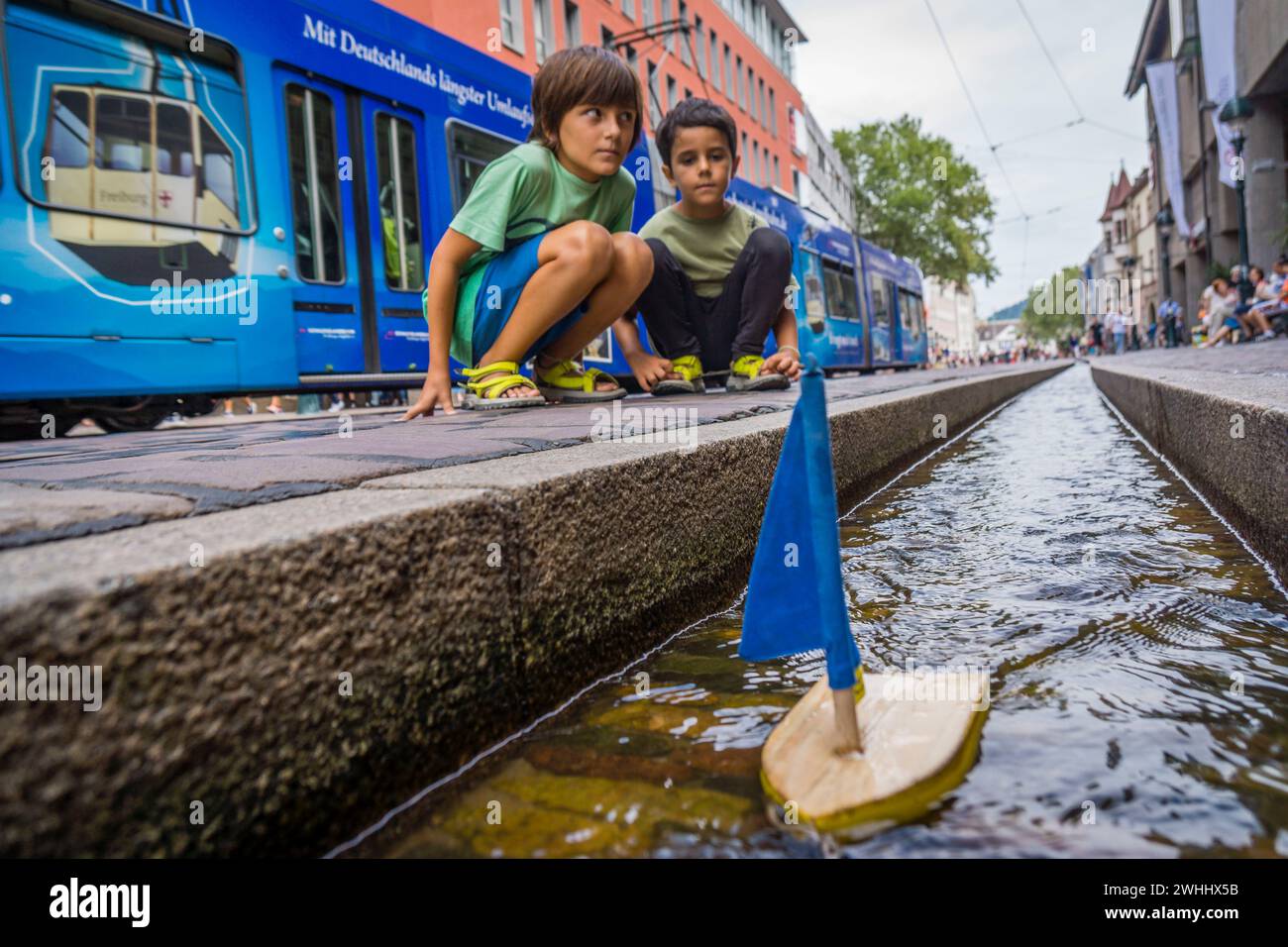 NiÃ±os jugando con un barquito de madera en los canales de agua Foto Stock