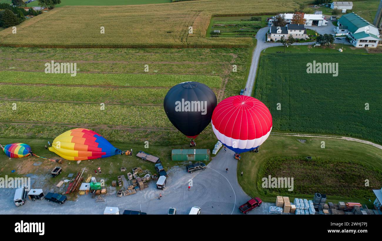 Vista dei droni su numerose e colorate mongolfiere che atterrano nelle fattorie, nei parcheggi e nelle case Foto Stock