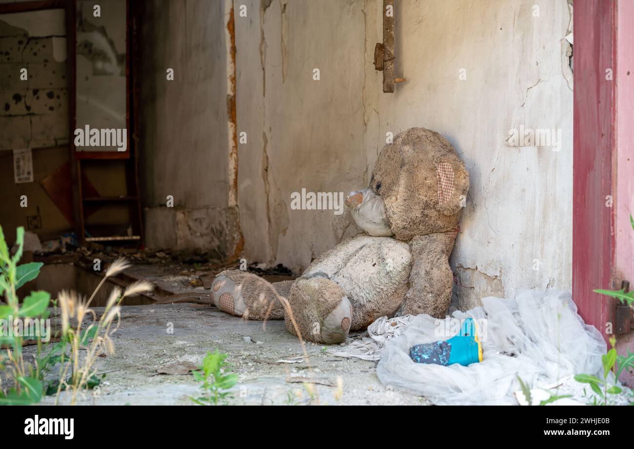 Peluche per bambini vicino al muro di una casa distrutta in Ucraina Foto Stock