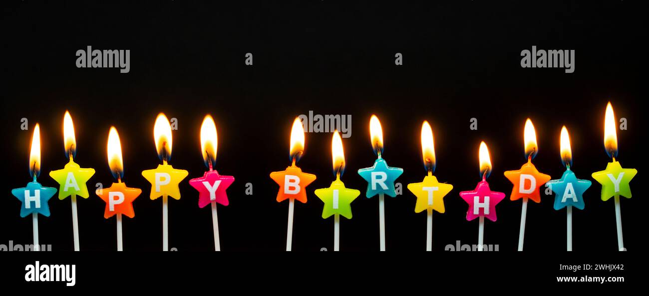 Bruciare candele con le parole Happy Birthday, candele che bruciano in fila lunga, isolate su nero scuro b Foto Stock