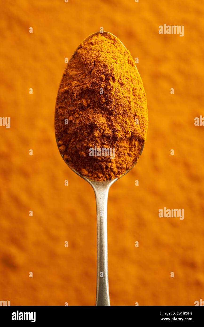 Radice curcuma macinata su un cucchiaio di metallo, vista dall'alto Foto Stock