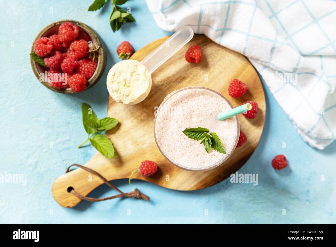 Latte fresco, lamponi bevono su una tavola di legno su fondo di pietra, frullato proteico con frutti di bosco freschi. Vista dall'alto. Foto Stock