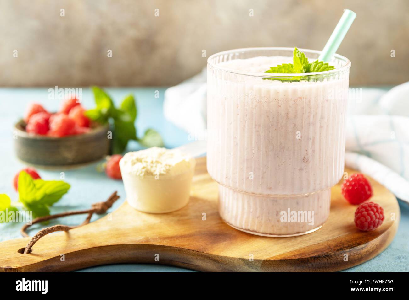 Latte fresco, lamponi bevono su una tavola di legno su uno sfondo di pietra, frullato proteico con frutti di bosco freschi. Copia spazio. Foto Stock