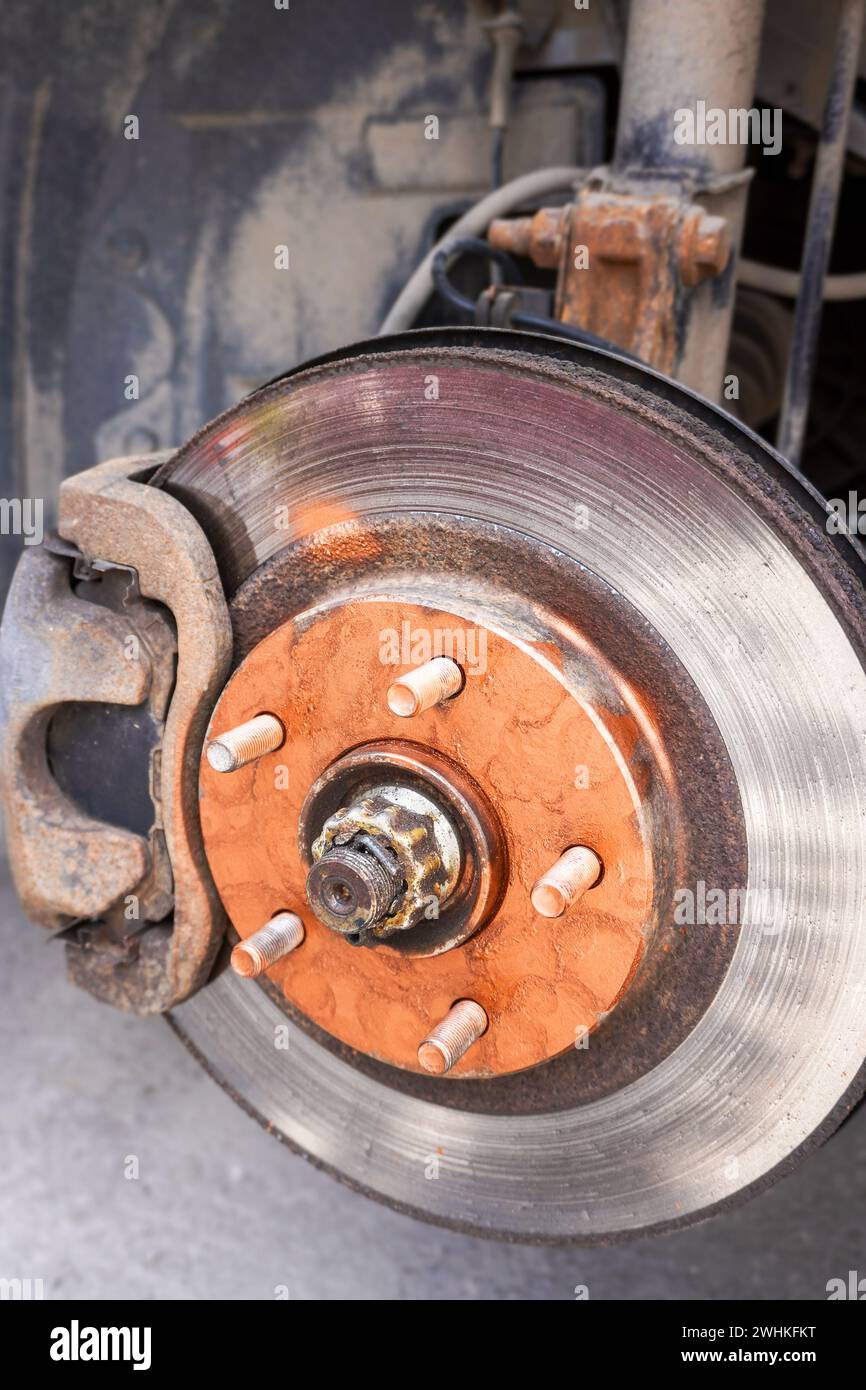 Un vecchio disco del freno dell'automobile arrugginito è lubrificato con grasso di rame prima di installare una ruota dell'automobile Foto Stock
