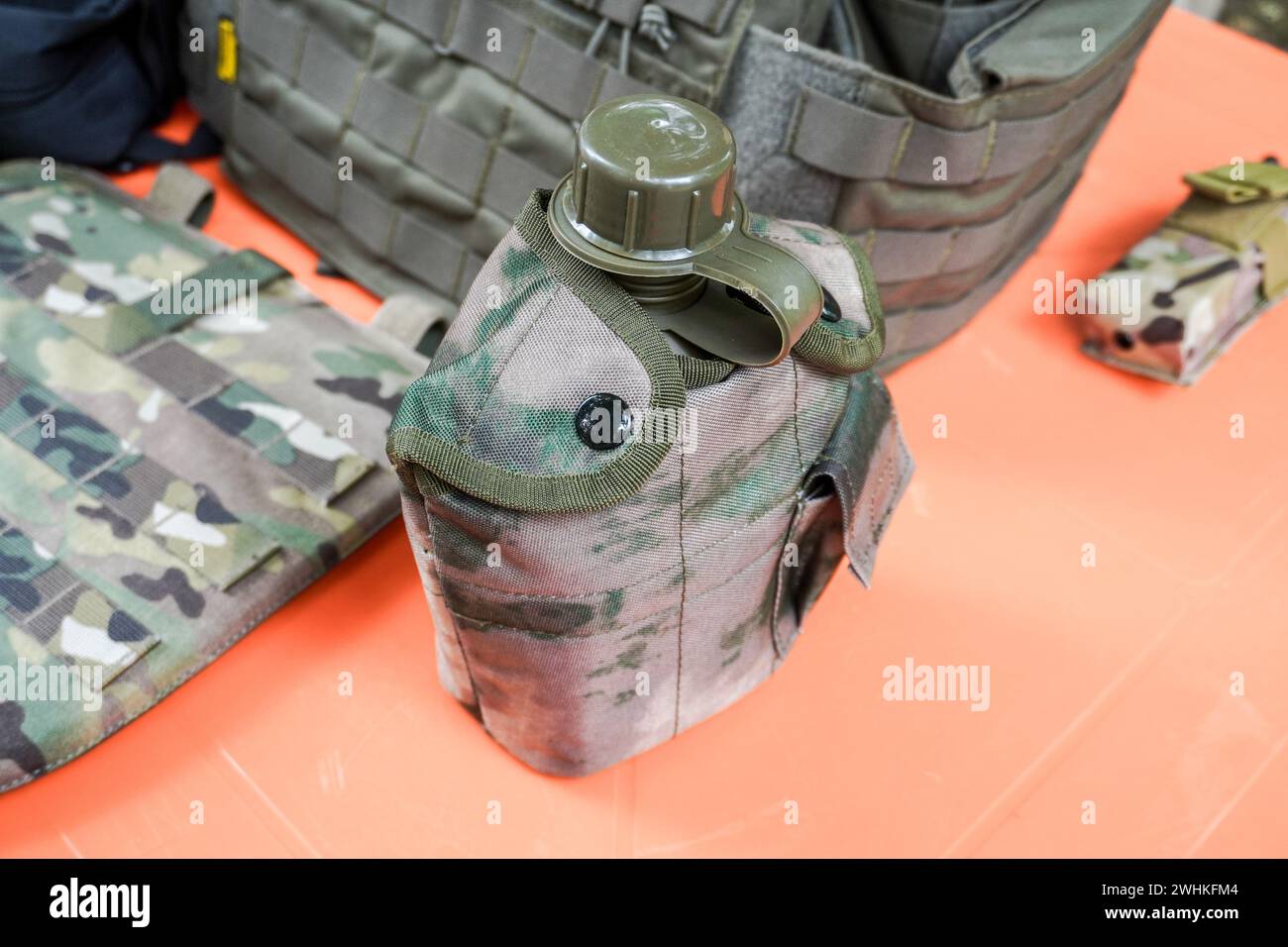 Beuta d'acqua in plastica militare con copertura in tessuto protettivo mimetico. Bottiglia verde in plastica militare con fabrick protettivo Foto Stock