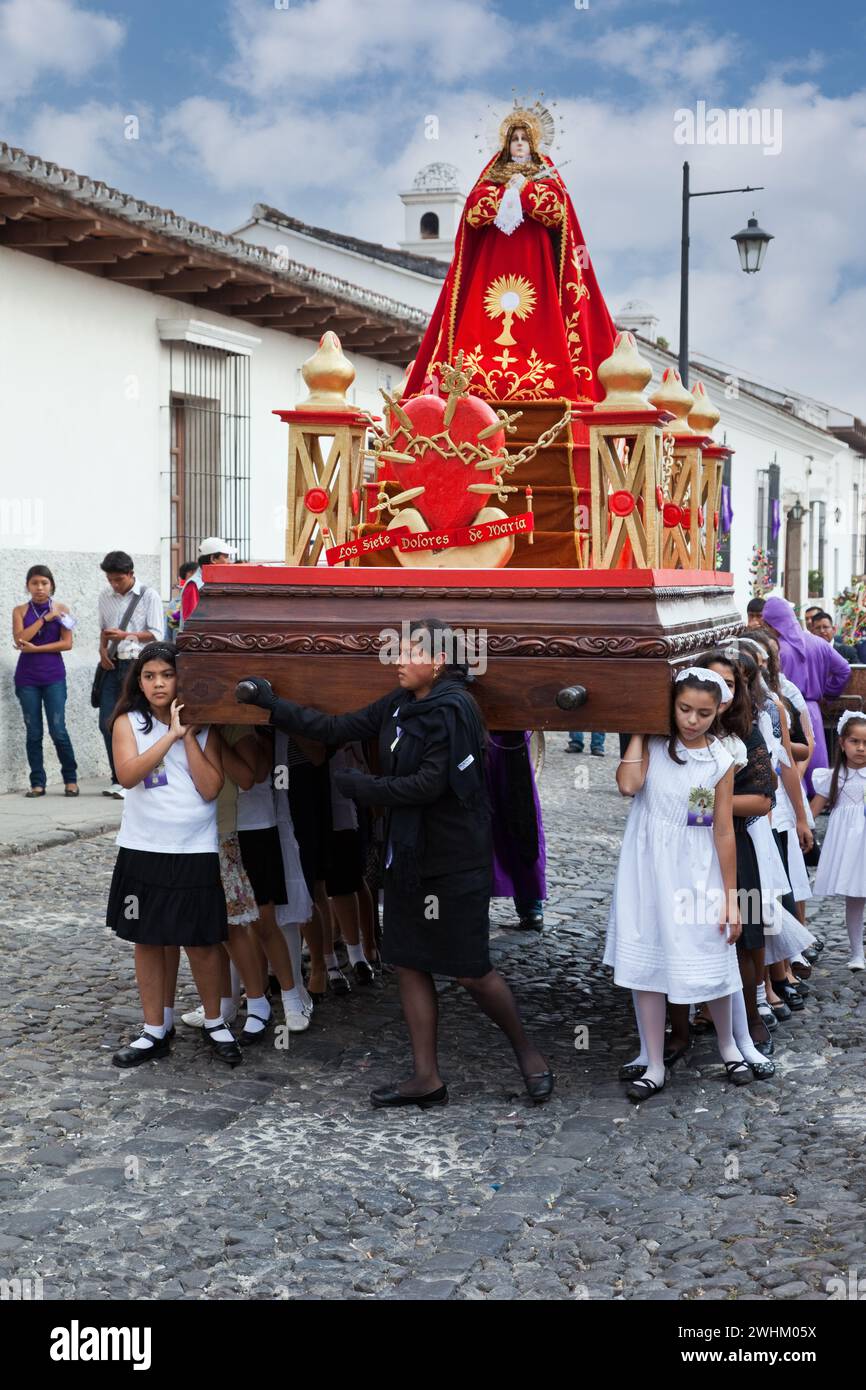Antigua, Guatemala. Semana Santa (settimana Santa). Le ragazze giovani portano un'Anda (float) in una processione religiosa. Foto Stock