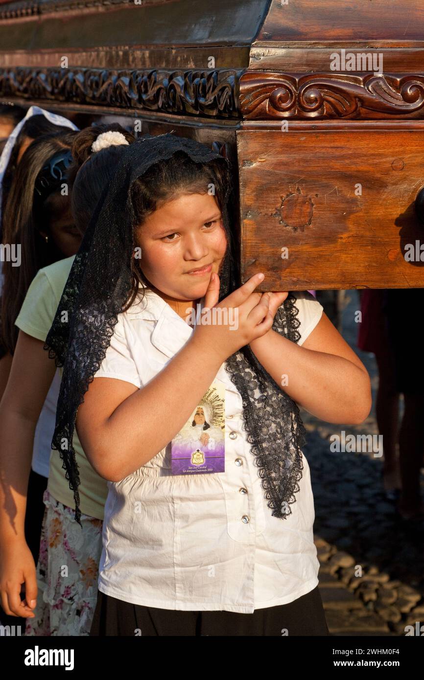 Antigua, Guatemala. Semana Santa (settimana Santa). Giovane ragazza che porta un Anda (galleggiante) della Vergine Maria in una Processione religiosa. Foto Stock