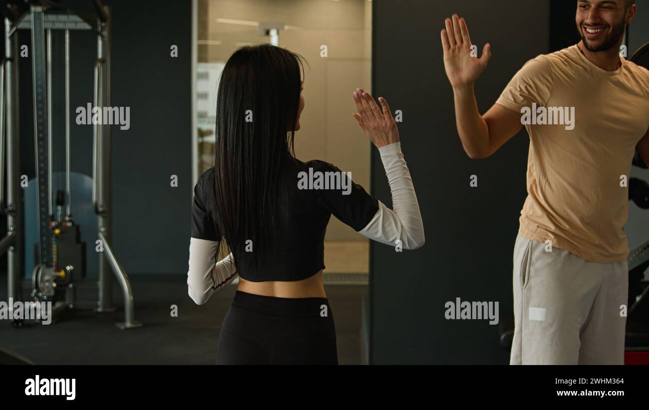 Vista sul retro silhouette sportiva donna fitness trainer camminare con bottiglia d'acqua nel club sportivo salutare sportivo afroamericano che si esercita in palestra due Foto Stock