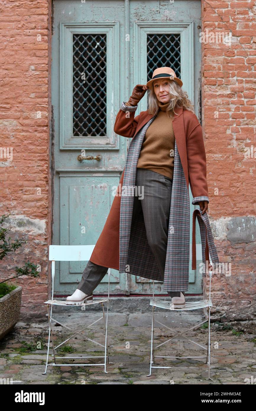 Donna con cappotto in terracotta e guanti in pelle Foto Stock
