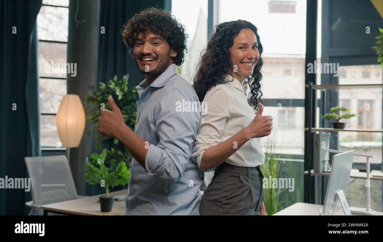 Entusiasti colleghi multirazziali partner commerciali uomo d'affari indiano arabo e donna ispanica colleghi d'affari che guardano alla telecamera felice Foto Stock