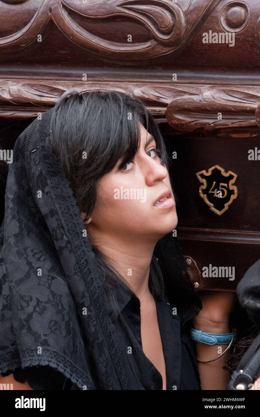 Antigua, Guatemala. Sabato Santo. Donna sotto il peso dell'Anda aiuta a portare nella Processione della Vergine della solitudine (Virgen Foto Stock