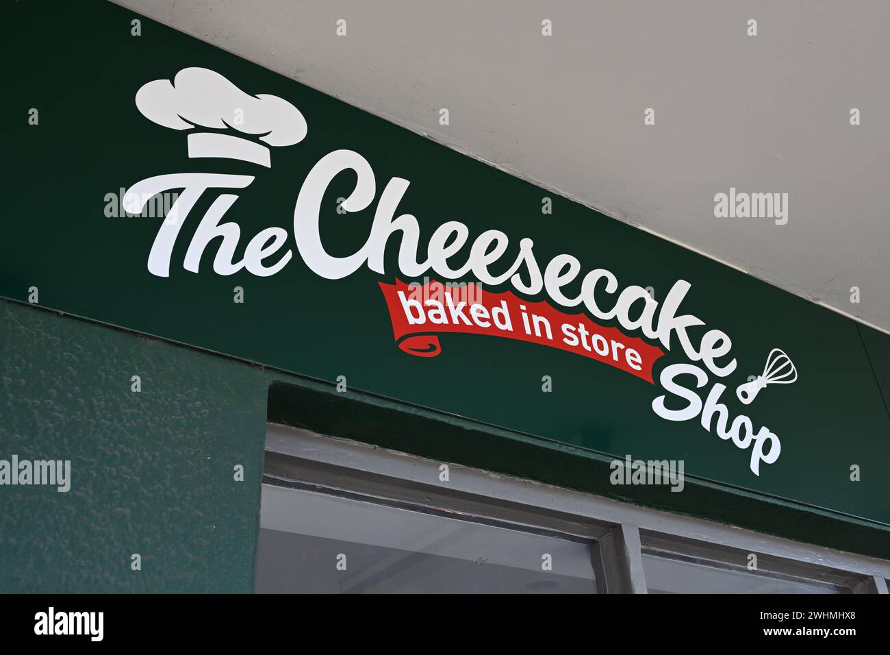 Il logo del Cheesecake Shop, con cappello e frusta dello chef, sopra l'ingresso di uno dei loro negozi nella periferia di Melbourne Foto Stock