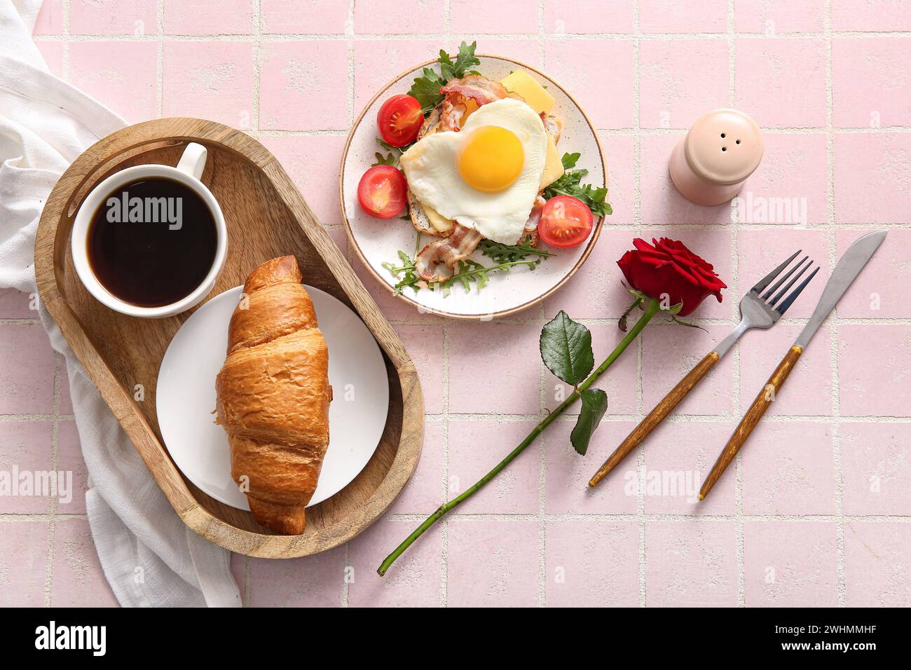 Composizione con gustoso uovo fritto nel piatto, croissant e tazza di caffè su sfondo leggero Foto Stock