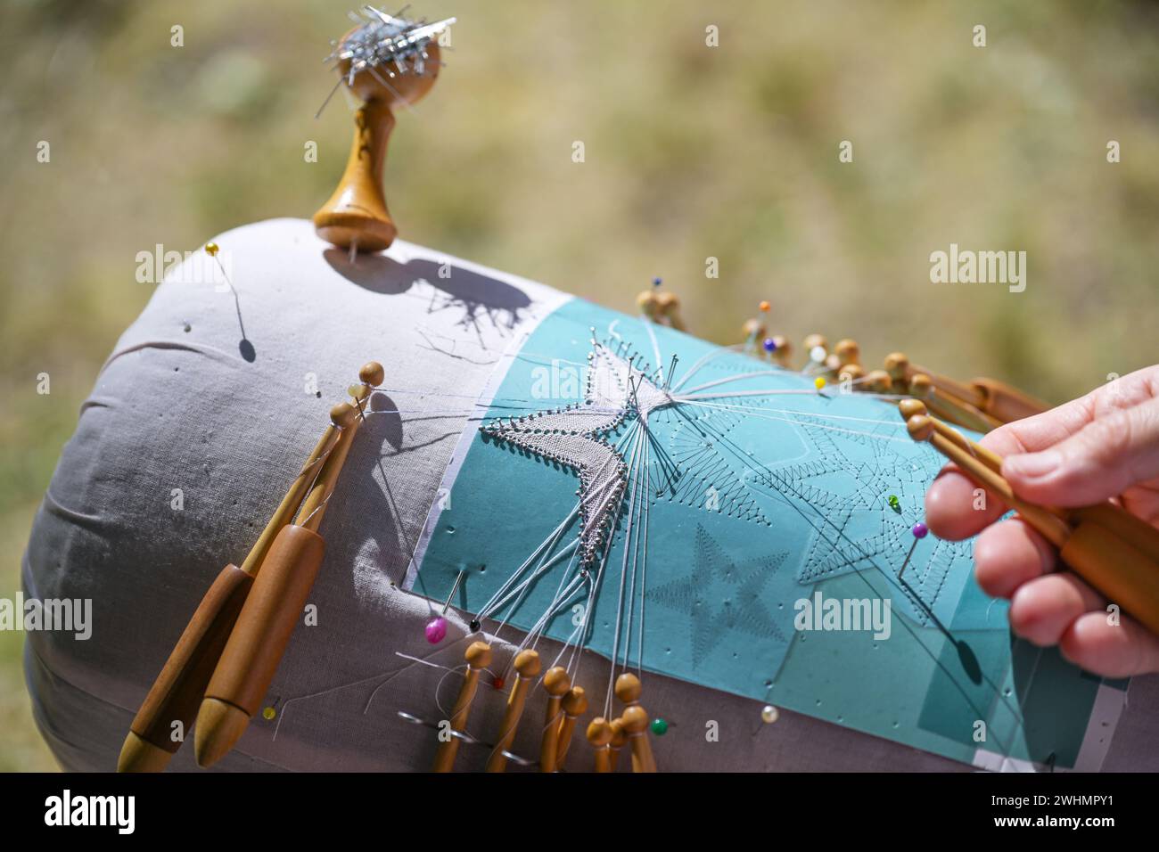 Processo di pizzo a forma di stella, le mani gestiscono i fili con l'aiuto di bobine di legno per torcerli intorno a. Foto Stock