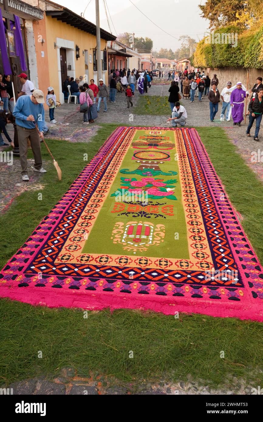 Antigua, Guatemala. Un alfombra (tappeto) di fiori, aghi di pino e altri materiali tradizionali decora la strada prima del passaggio di Foto Stock