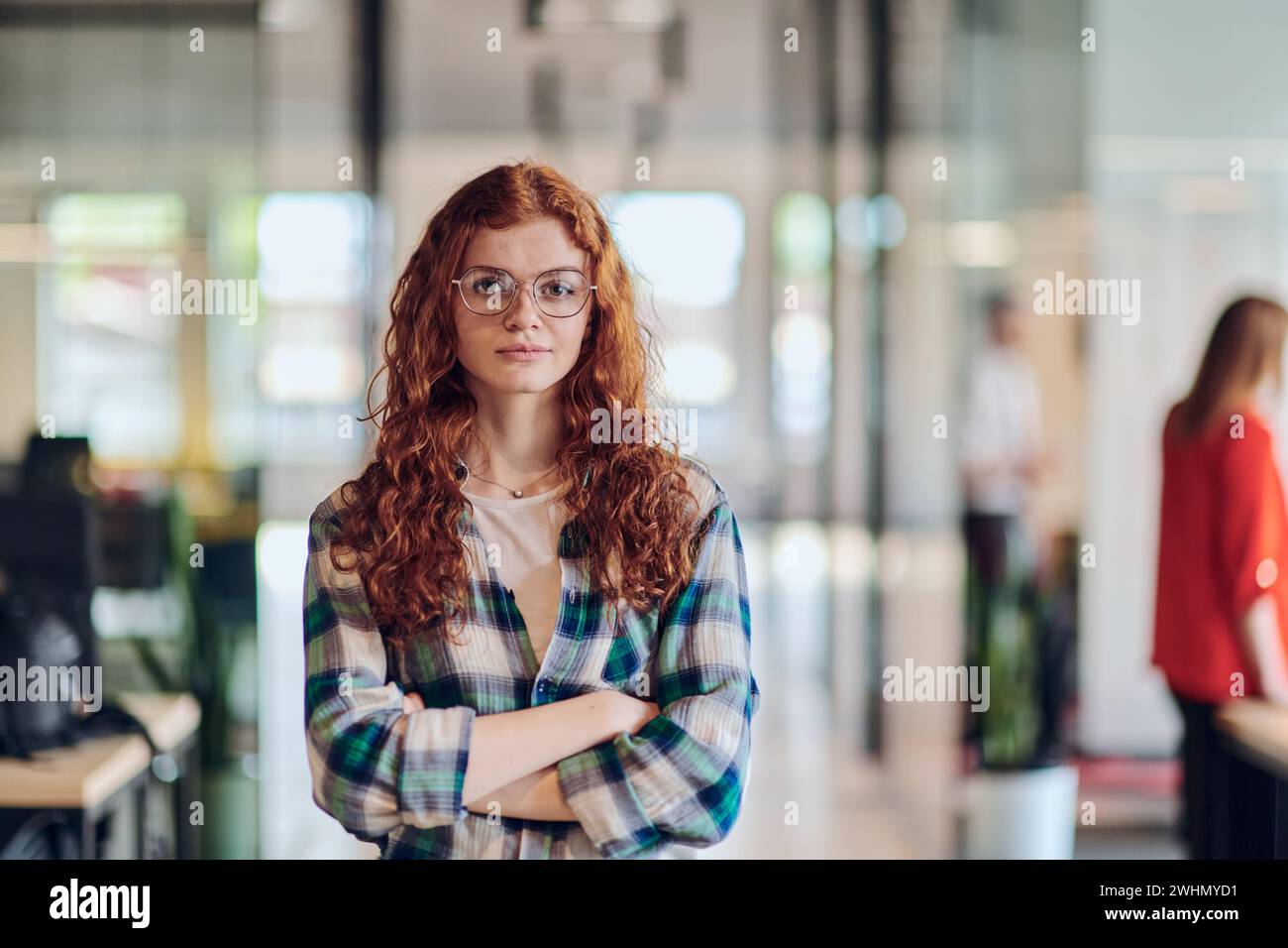 Un ritratto di una giovane donna d'affari con i moderni capelli arancioni cattura la sua presenza in un corridoio di una startup contemporanea Foto Stock