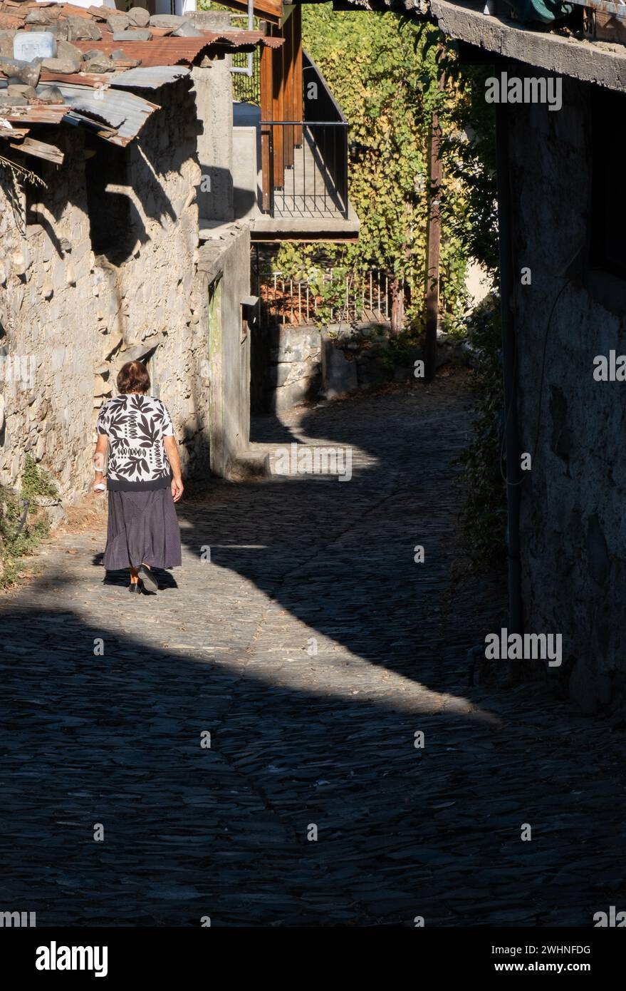Donna anziana che cammina nella strada in pietra di un villaggio tradizionale. Persone attive all'aperto Foto Stock