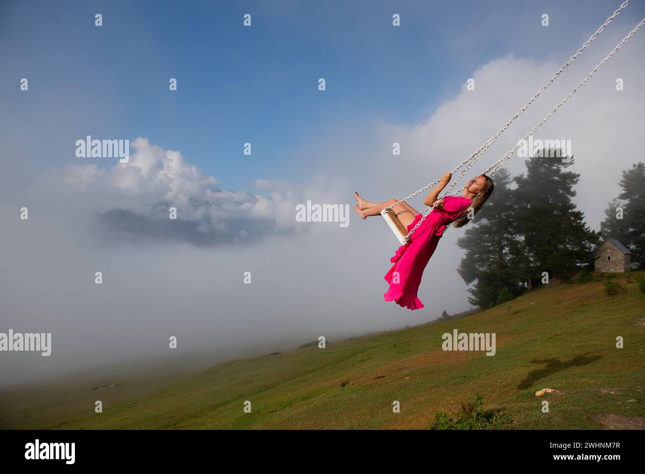 Ragazza, altalena e sinfonia di sorrisi ragazza con un vestito rosa Foto Stock