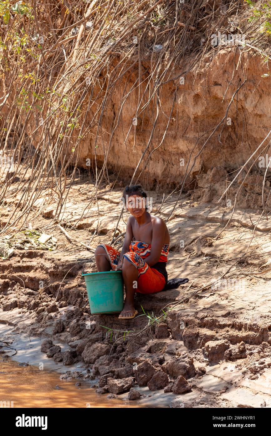 La vita rurale a Belo Sur Tsiribihina, Madagascar, un momento quotidiano di una donna che raccoglie acqua vicino al fiume a Belo Sur Tsiribihi Foto Stock