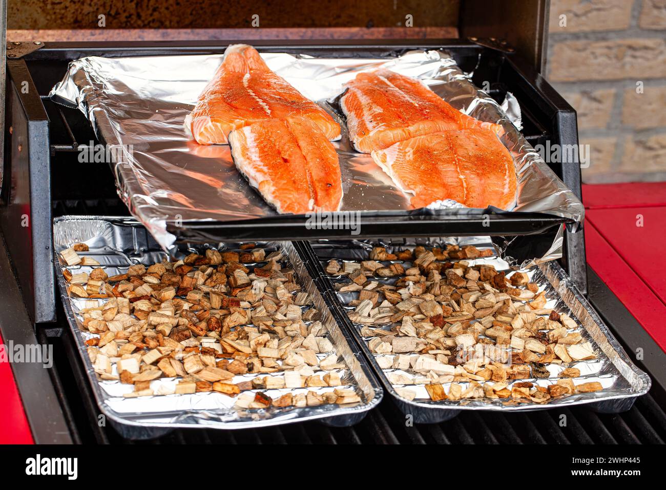 Primo piano di una cucina all'aperto con un lembo aperto che mostra bistecche fresche di salmone selvatico da affumicare con legno di mele e legno di quercia Foto Stock