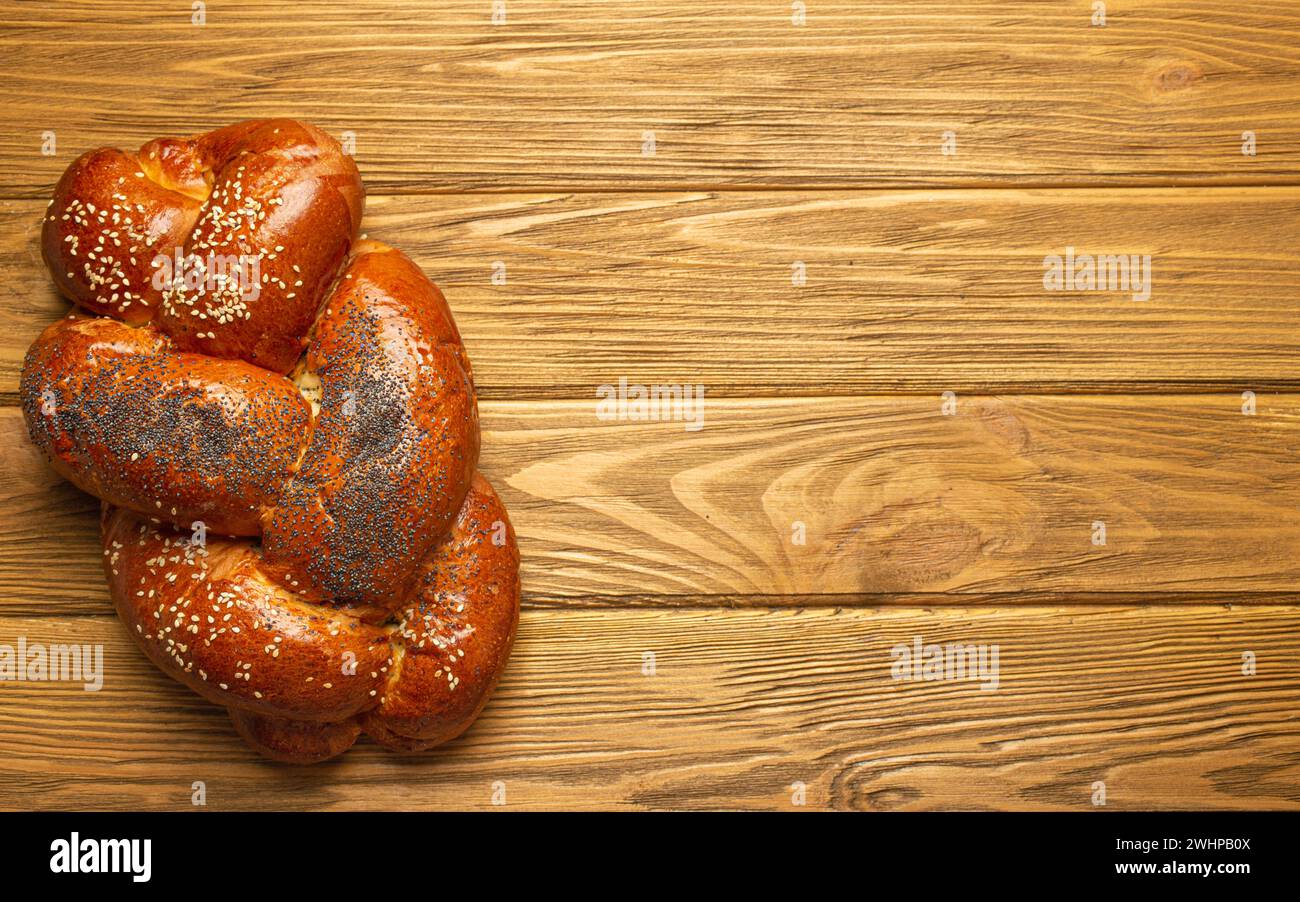 Pane Challah appena sfornato ricoperto di papavero e semi di sesamo, vista dall'alto su uno sfondo rustico in legno, tradizionale Jewi festivi Foto Stock