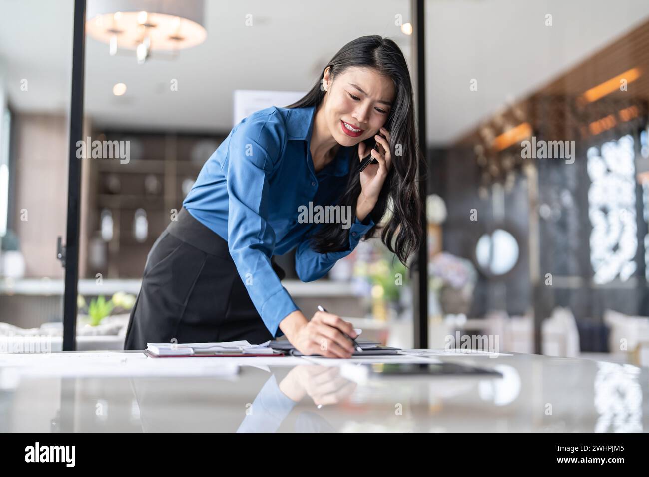BeautifulÂ donna segretaria asiatica fiduciosa intelligente donna d'affari professionale Â parlare su phoneÂ Â a officeà¹ƒ Foto Stock