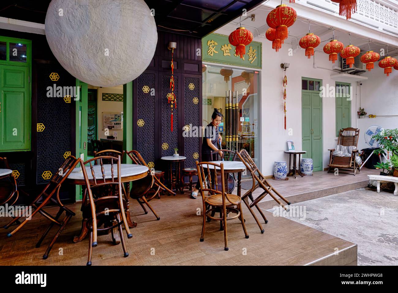 Un dipendente dell'ama Hostel a Chinatown, Bangkok, Tailandia, ex residenza in stile cinese, che abbellisce l'edificio Foto Stock