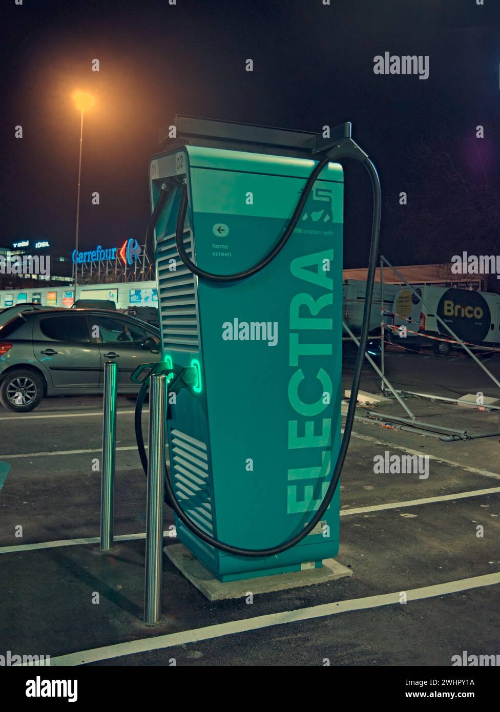 Bruxelles, Belgio. 6 febbraio 2024. Fotografia di strada. Città notturna. Stazione di ricarica Electra per auto vicino al centro commerciale Basilix. Foto Stock