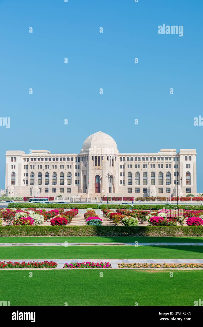 Vista frontale alla Corte Suprema dell'Oman a Mascate, Oman. Giardini assolati in primo piano. Foto Stock