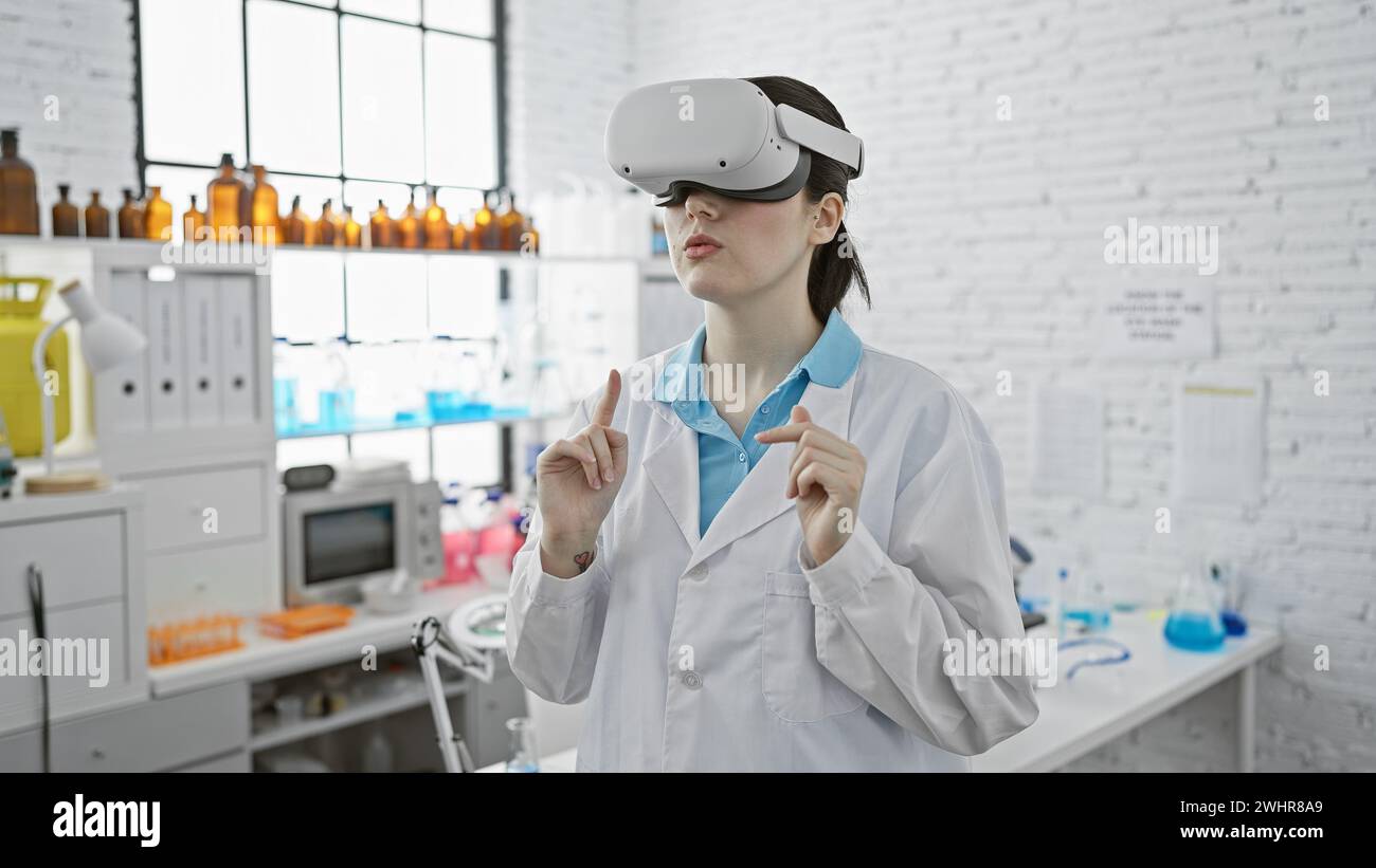 Una giovane donna caucasica che indossa occhiali per la realtà virtuale in un moderno ambiente di laboratorio, trasmettendo innovazione nella scienza. Foto Stock