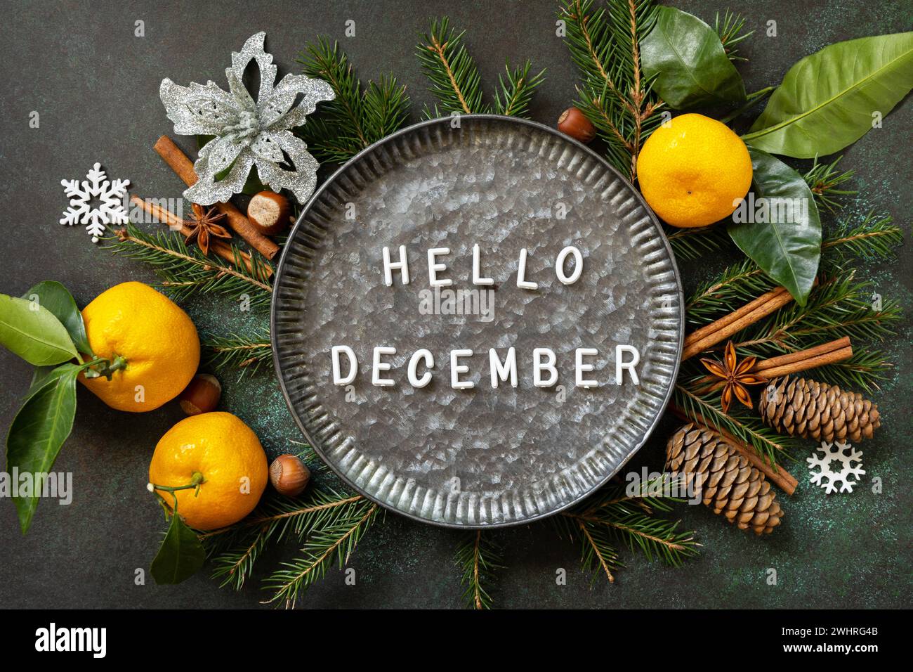 Ciao testo di dicembre. Composizione invernale con rami di abete, coni e tangerini. Atmosfera invernale accogliente. Biglietto d'auguri per le stagioni. Foto Stock