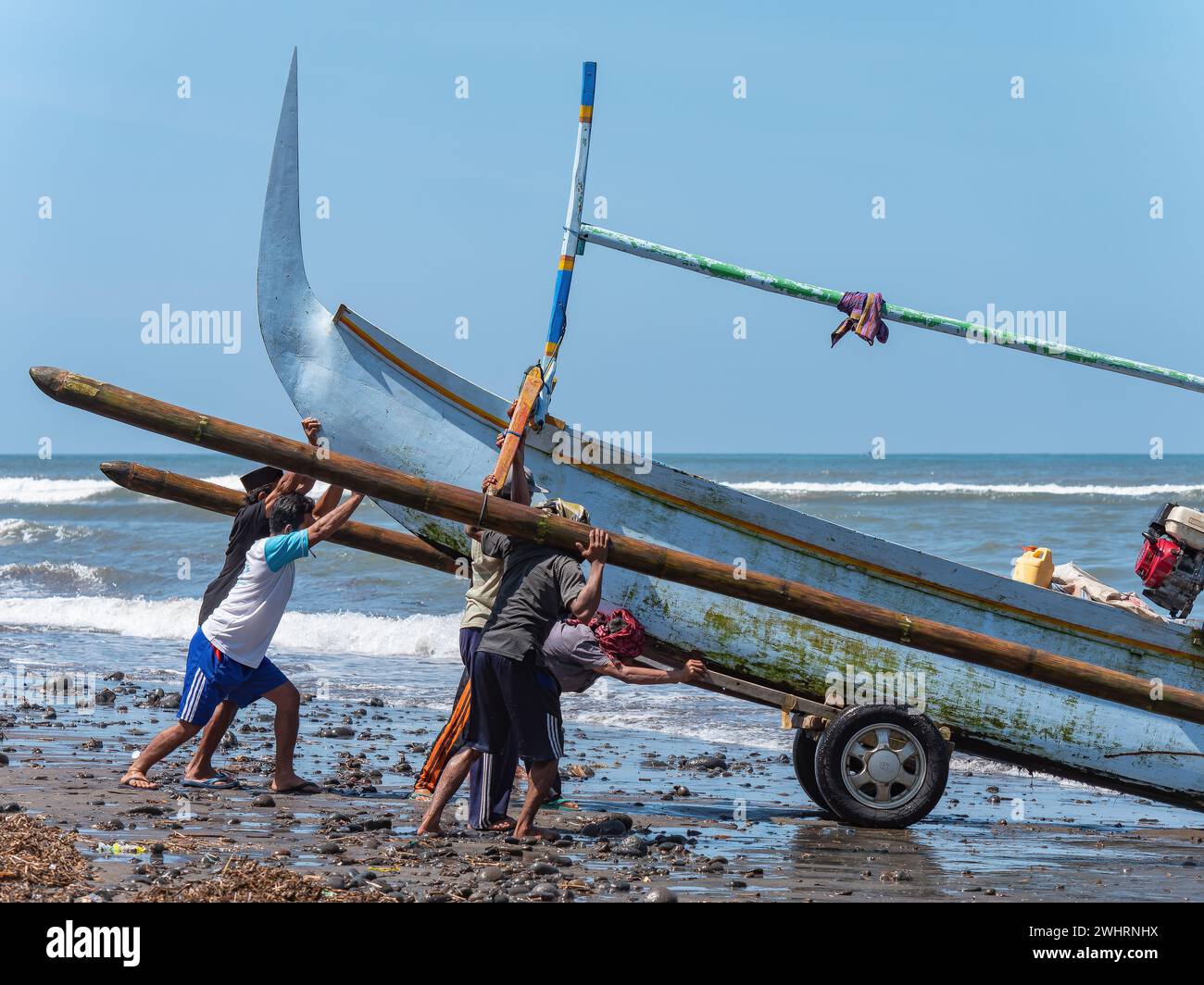 Tradizionale peschereccio indonesiano con gli stabilizzatori trainati su una spiaggia rocciosa a Medewi, sull'isola di Bali in Indonesia. Foto Stock