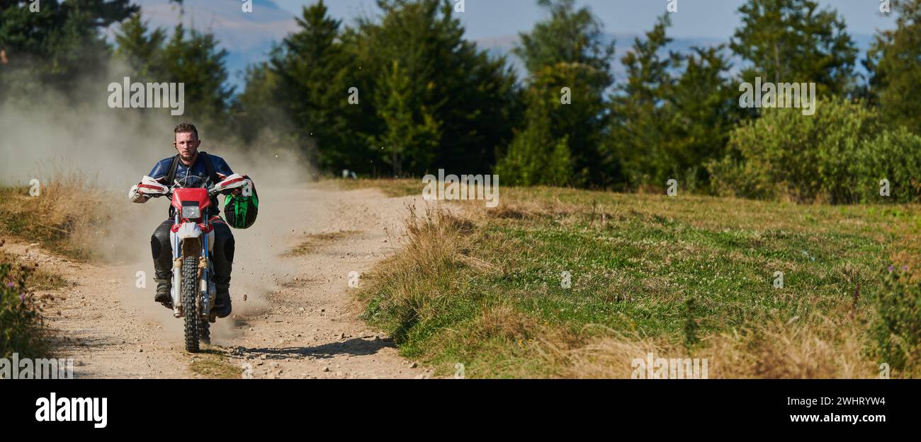 Un pilota professionista di motocross che guida in moto un insidioso sentiero fuoristrada nella foresta. Foto Stock