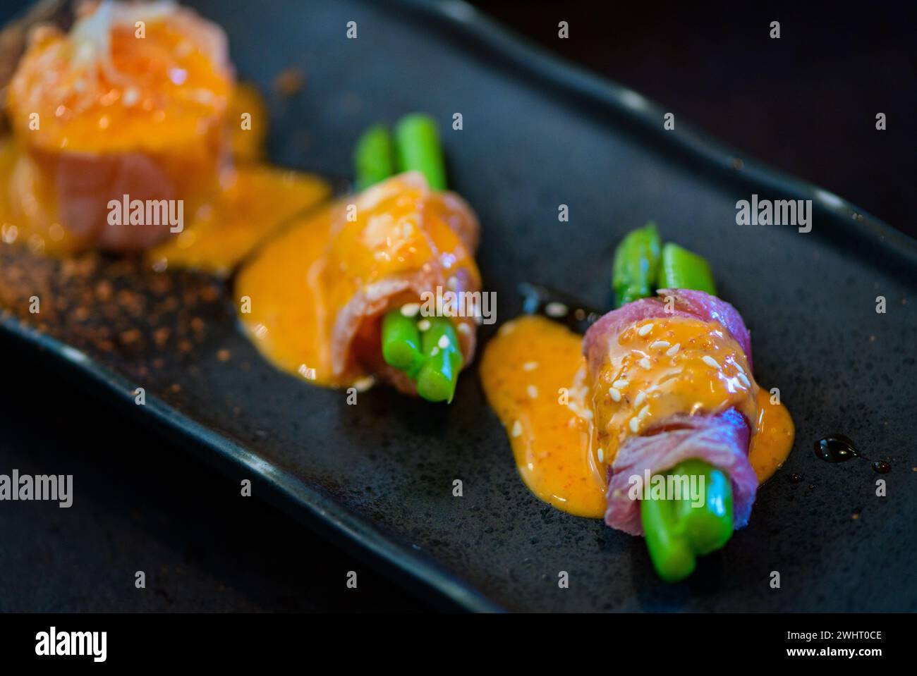 Wagyu con involtino di asparagi su piatto nero, Premium cucina giapponese a base di carne Foto Stock