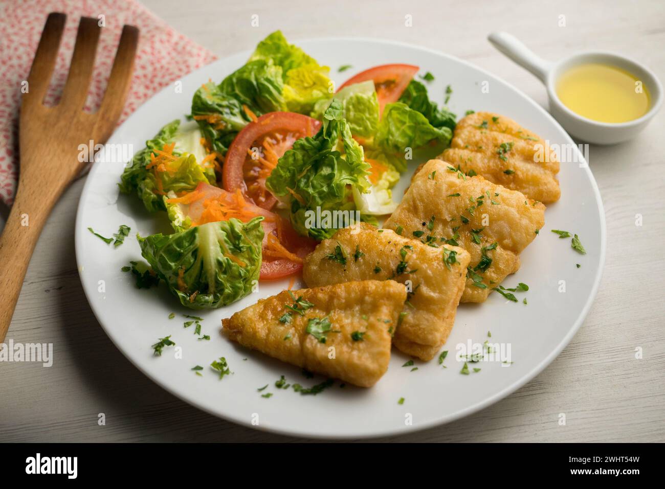Pesce bianco pastella servito con un'insalata di pomodoro. Foto Stock