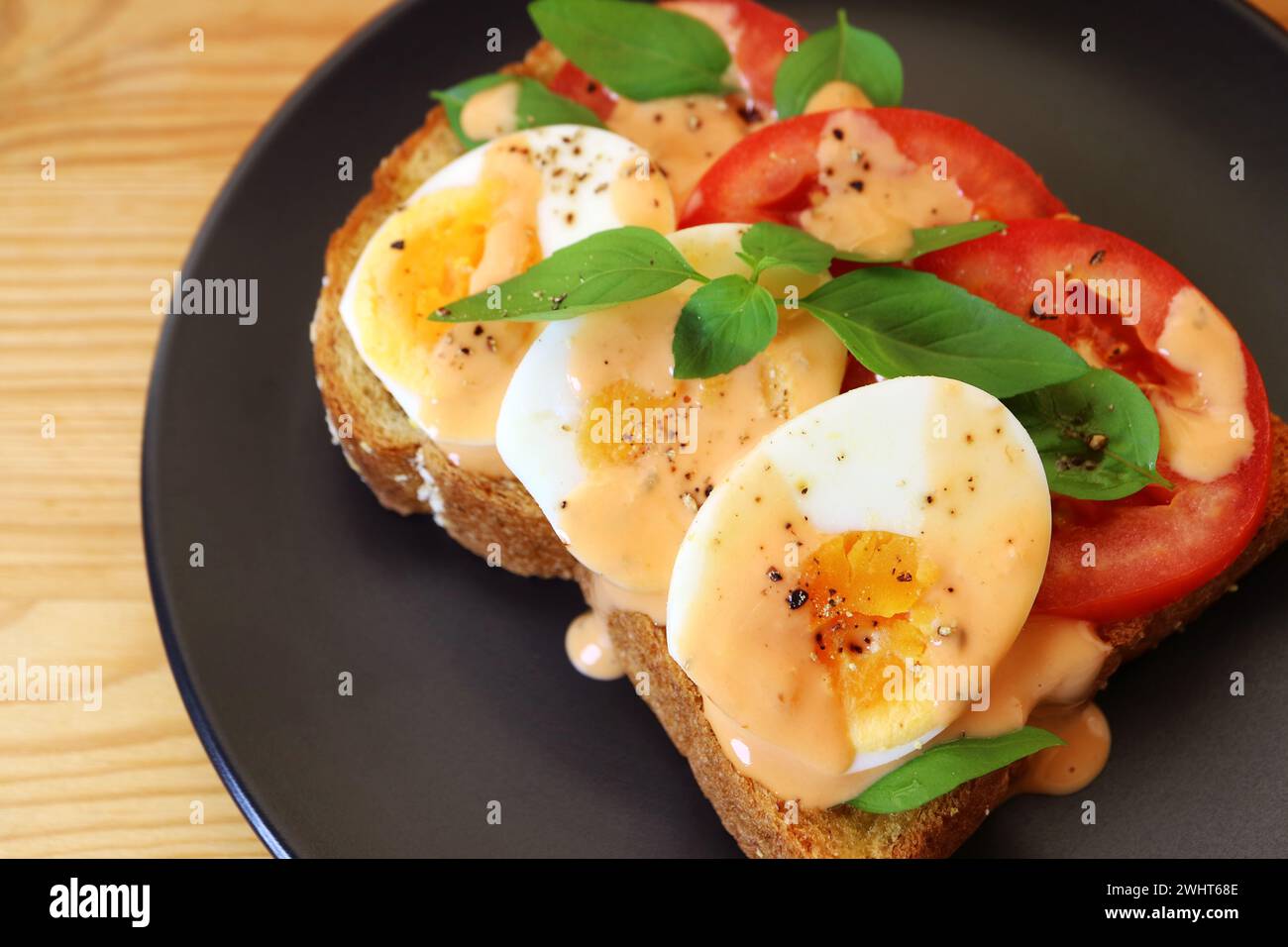 Primo piano del delizioso uovo sodo con panini aperti al basilico di pomodoro Foto Stock