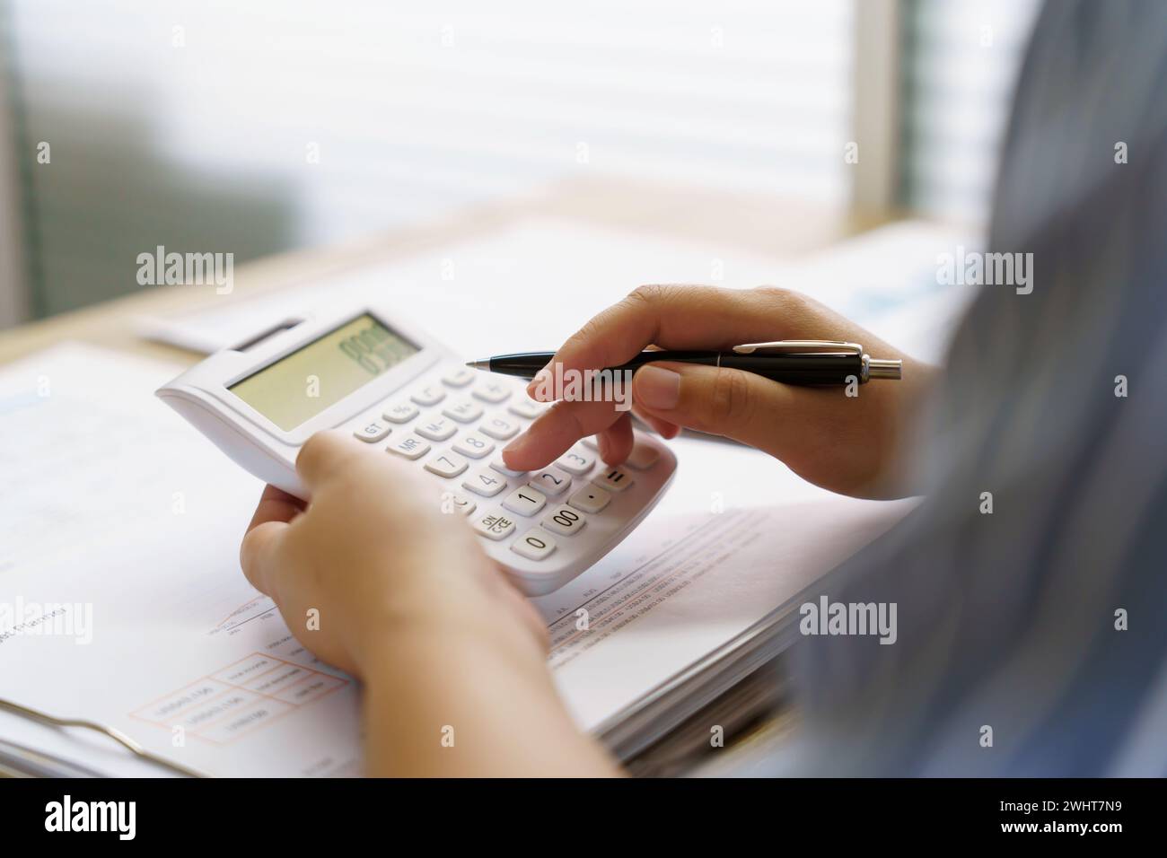 Imprenditrice contabile che analizza i grafici di investimento fattura e preme i pulsanti di calcolo sui documenti. Contabilità Foto Stock