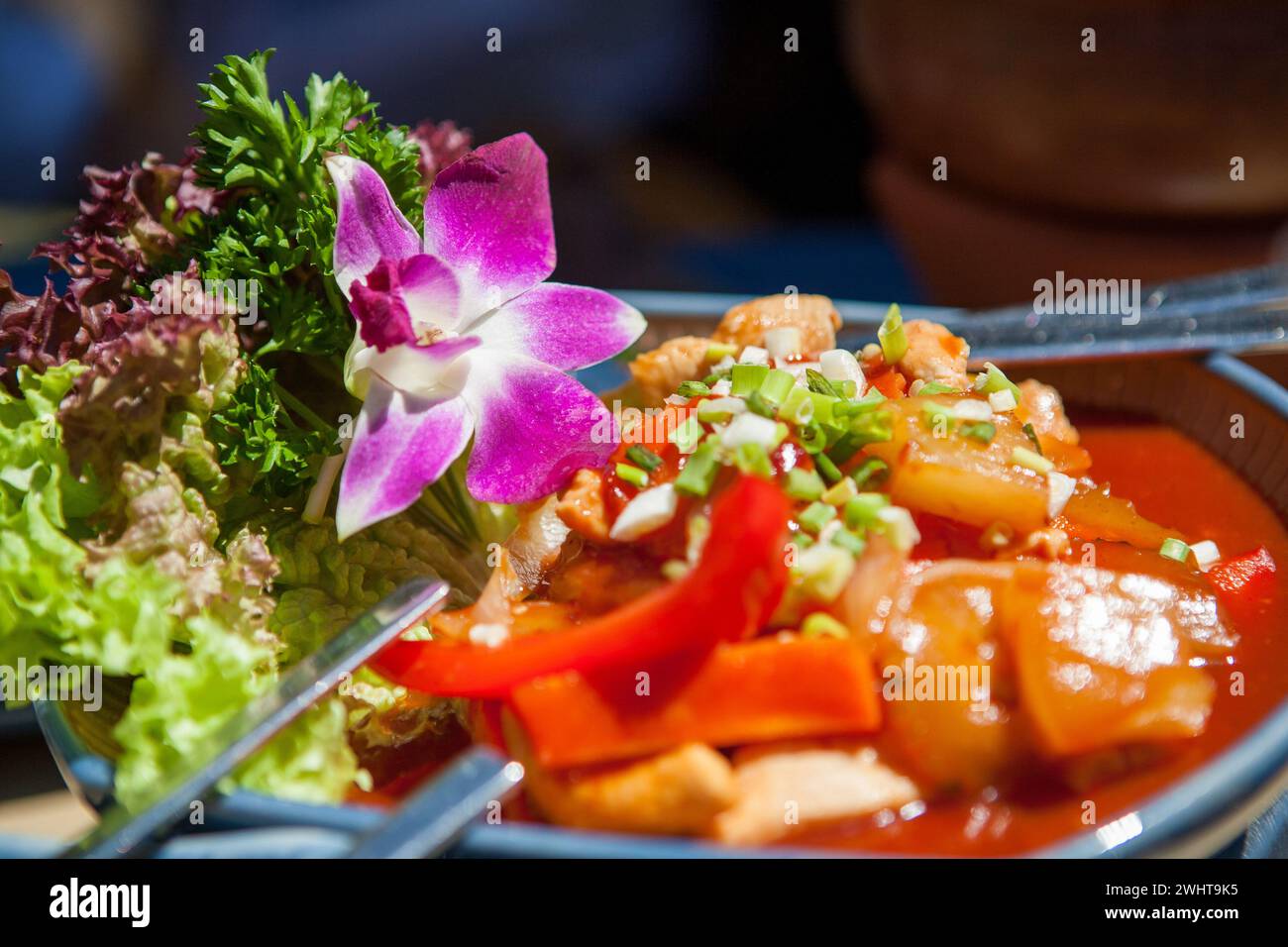 Squisita arte culinaria tailandese: Vibrante piatto thailandese con decorazione di fiori rosa Foto Stock