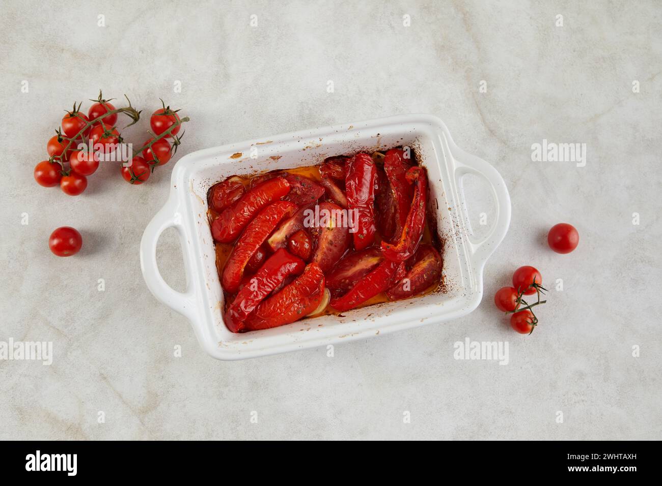 Pomodori e peperoni al forno con aglio ed erbe aromatiche in ceramica Foto Stock