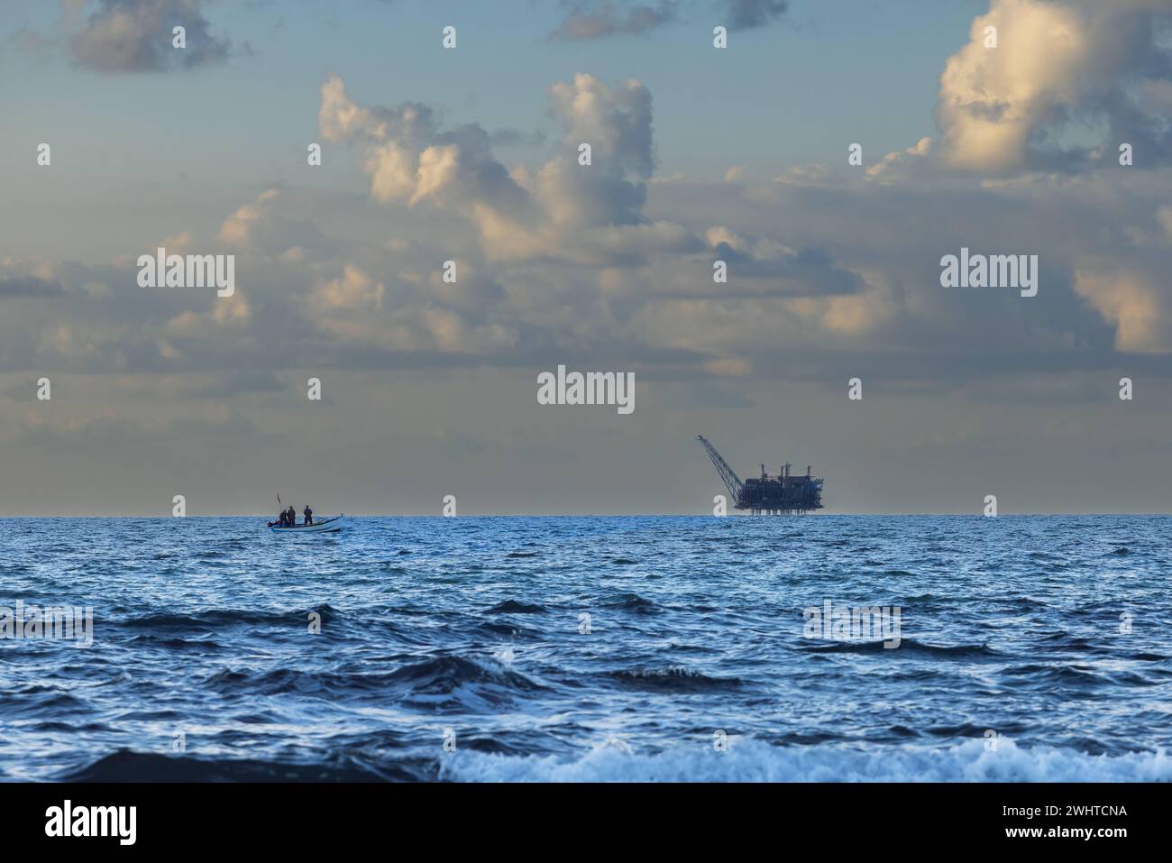 Barca a vela verso la piattaforma di gas contro il cielo al tramonto in Israele Foto Stock
